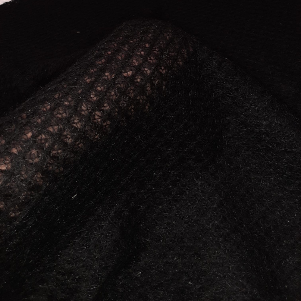 Close-up van open gebreide zwarte stof met dikke en dunne garens – zachte mohairmix uit deadstock collectie.